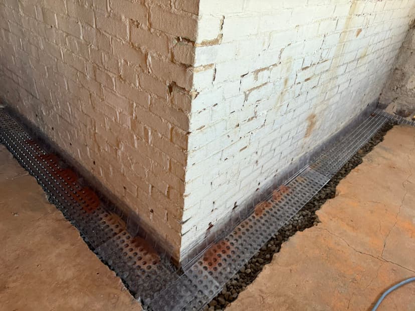 HydroHelp911 Crawl Space & Foundation Repair installing interior drainage system with drainage matting in a basement.