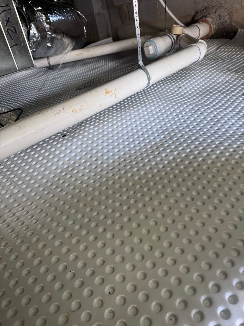 HydroHelp911 Crawl Space & Foundation Repair installing drainage matting and PVC pipes in a crawl space.
