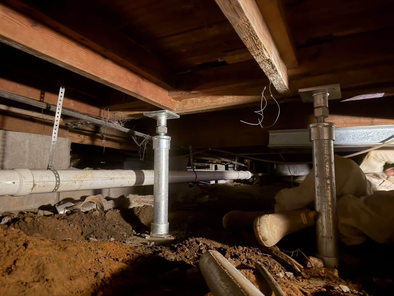 HydroHelp911 Crawl Space & Foundation Repair installing steel support jacks in a crawl space to stabilize sagging floors