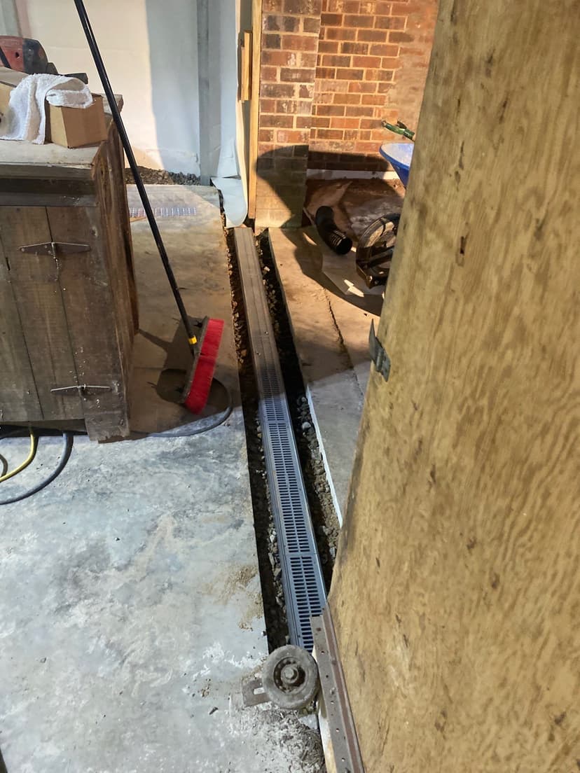 HydroHelp911 Crawl Space & Foundation Repair installing an interior drainage system in a basement with concrete floors.