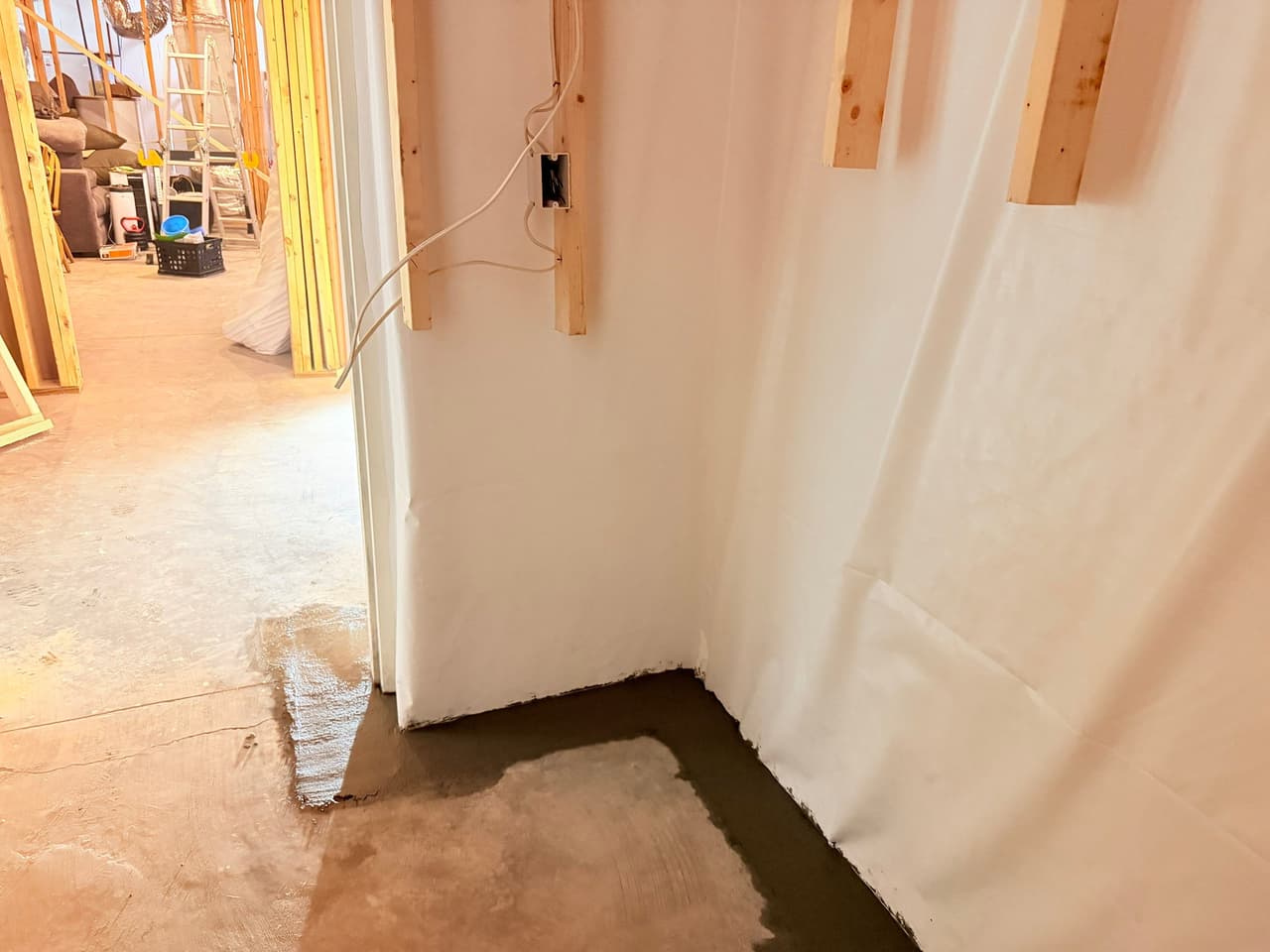 HydroHelp911 Crawl Space & Foundation Repair installing an interior drainage system in a basement with visible pooled water.