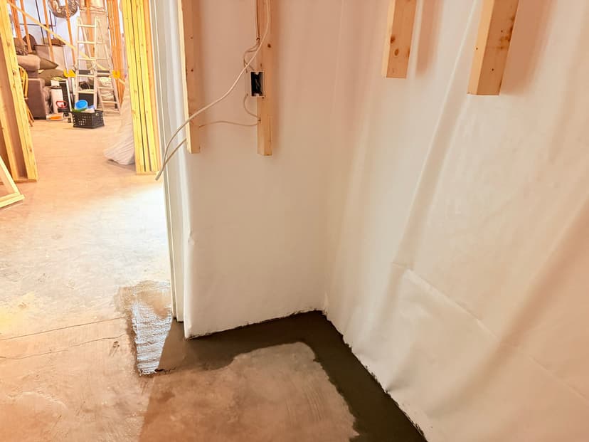 HydroHelp911 Crawl Space & Foundation Repair installing an interior drainage system in a basement with visible pooled water.