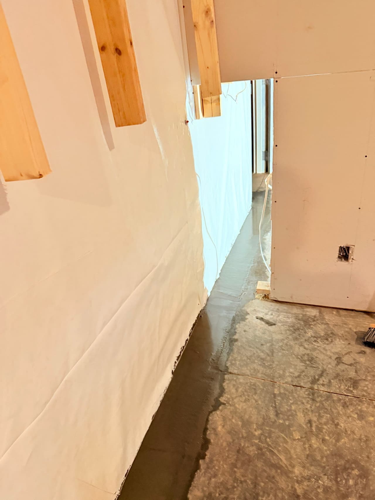 HydroHelp911 Crawl Space & Foundation Repair installing an interior drainage system and vapor barrier in a basement.
