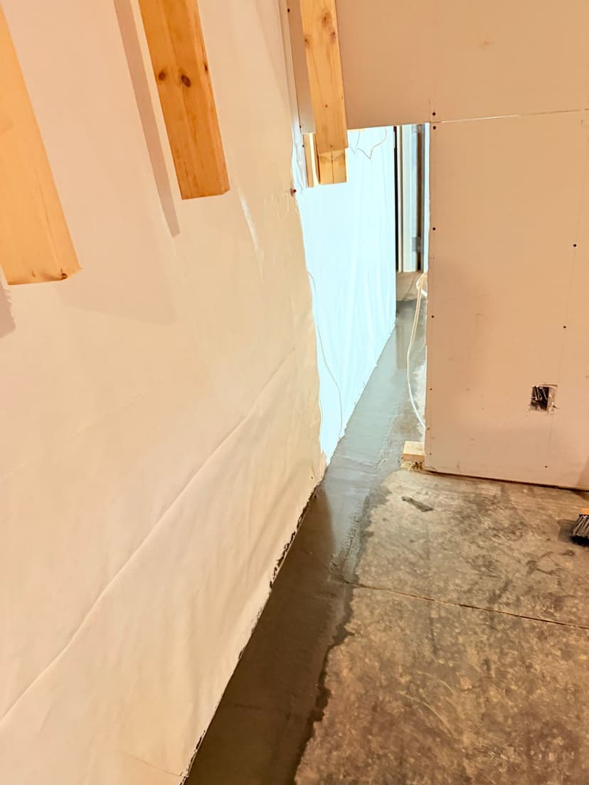 HydroHelp911 Crawl Space & Foundation Repair installing an interior drainage system and vapor barrier in a basement.