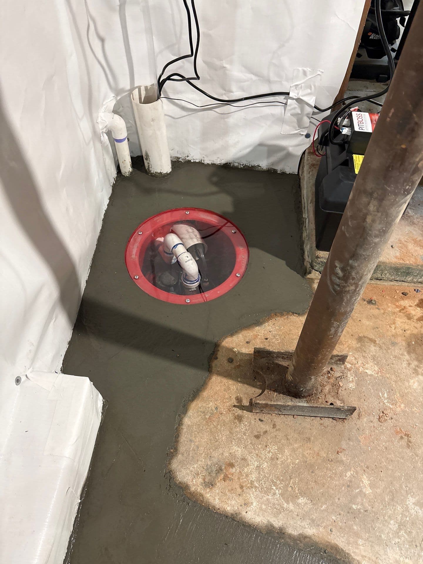 HydroHelp911 Crawl Space & Foundation Repair installing a backup sump pump system and vapor barrier in a basement.