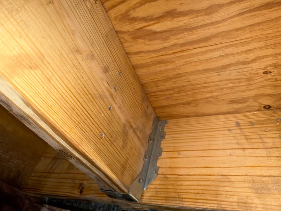 HydroHelp911 Crawl Space & Foundation Repair installing joist hangers on floor joists in a crawl space.