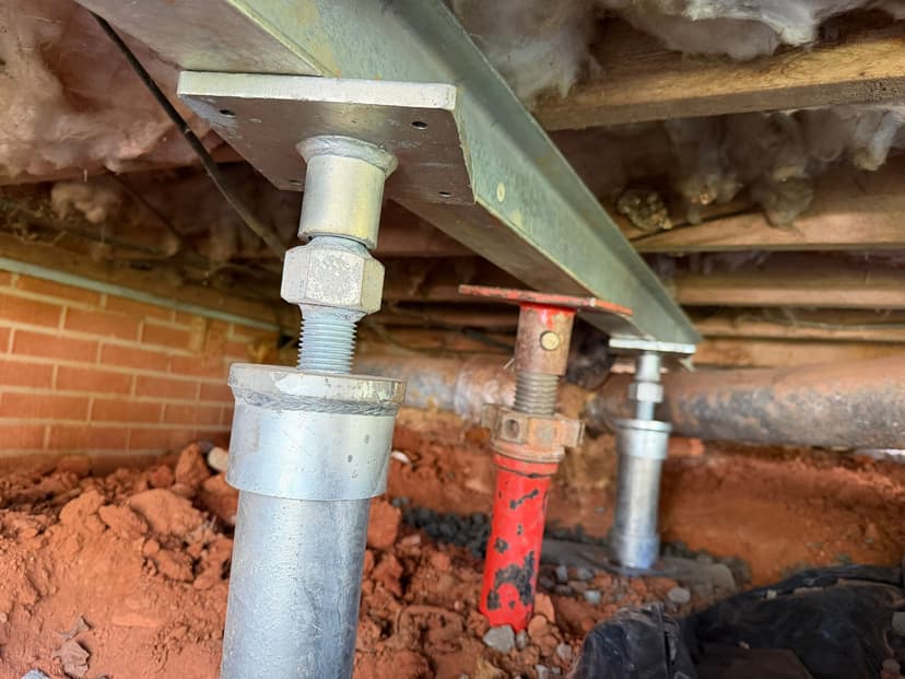 HydroHelp911 Crawl Space & Foundation Repair installing adjustable steel jacks for crawl space structural repair.