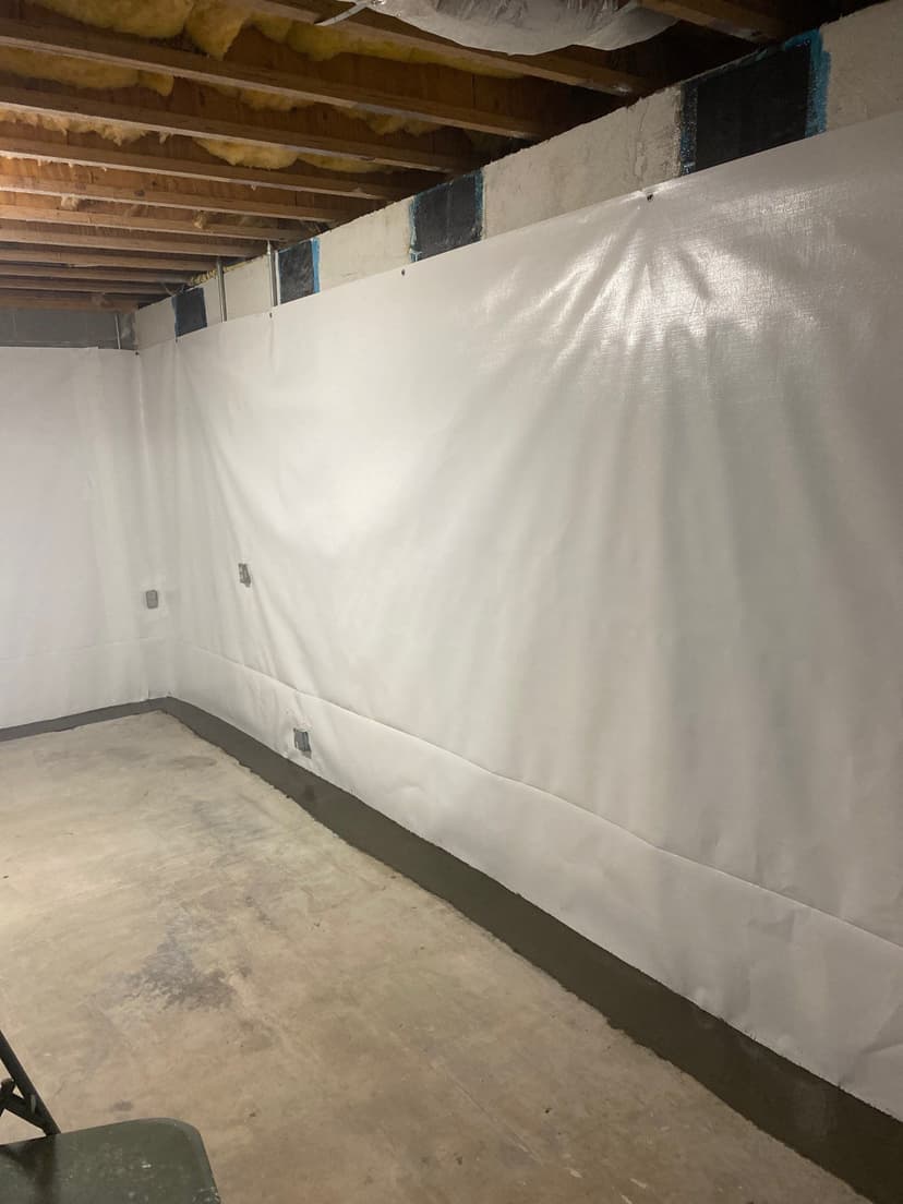 HydroHelp911 Crawl Space & Foundation Repair installing a white vapor barrier and carbon fiber reinforcement in a basement.