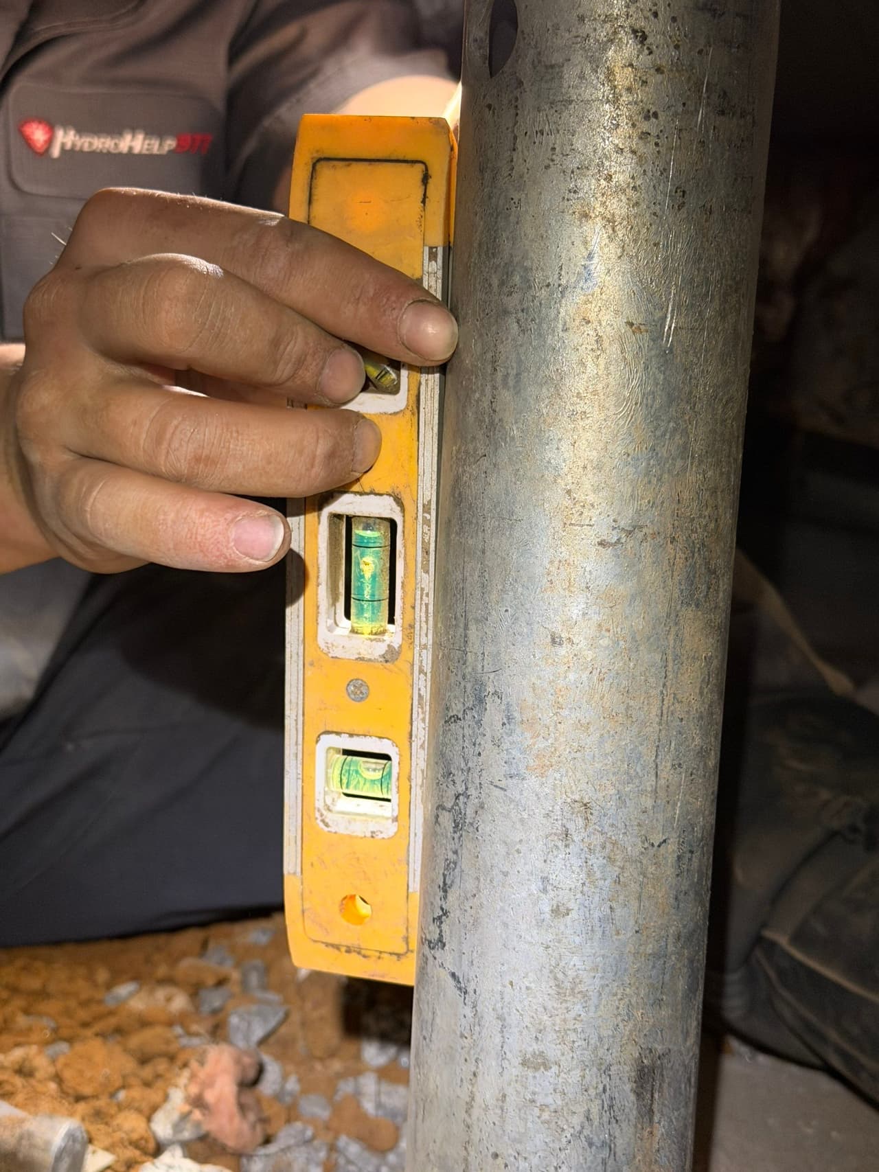 HydroHelp911 Crawl Space & Foundation Repair technician using a spirit level on a steel crawl space jack.