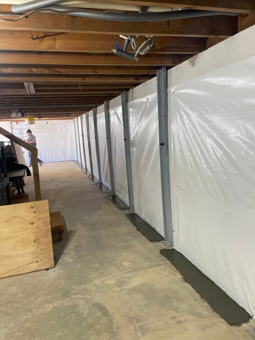 HydroHelp911 Crawl Space & Foundation Repair installing an interior drainage system and vapor barrier in a basement.