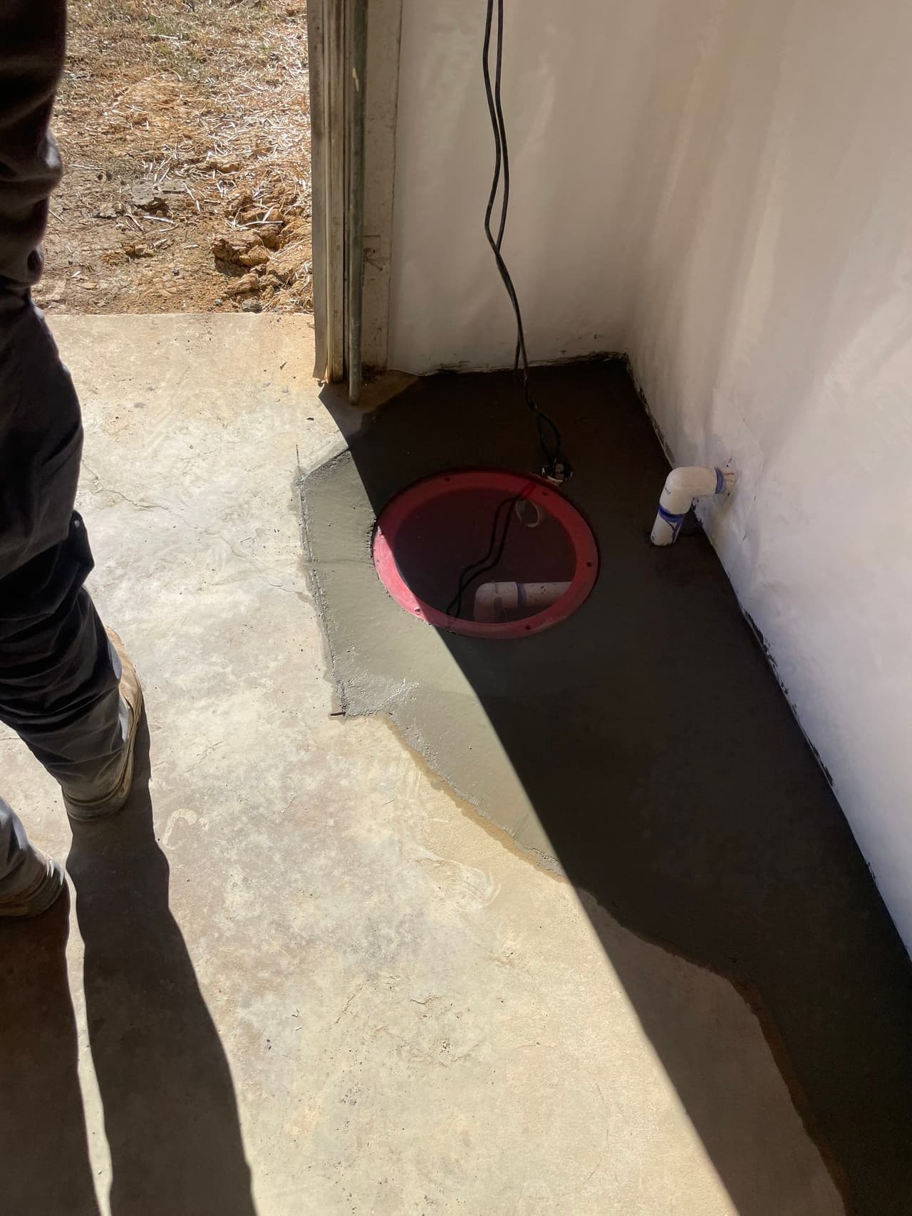 HydroHelp911 Crawl Space & Foundation Repair installing a new sump pump and discharge pipe in a basement.