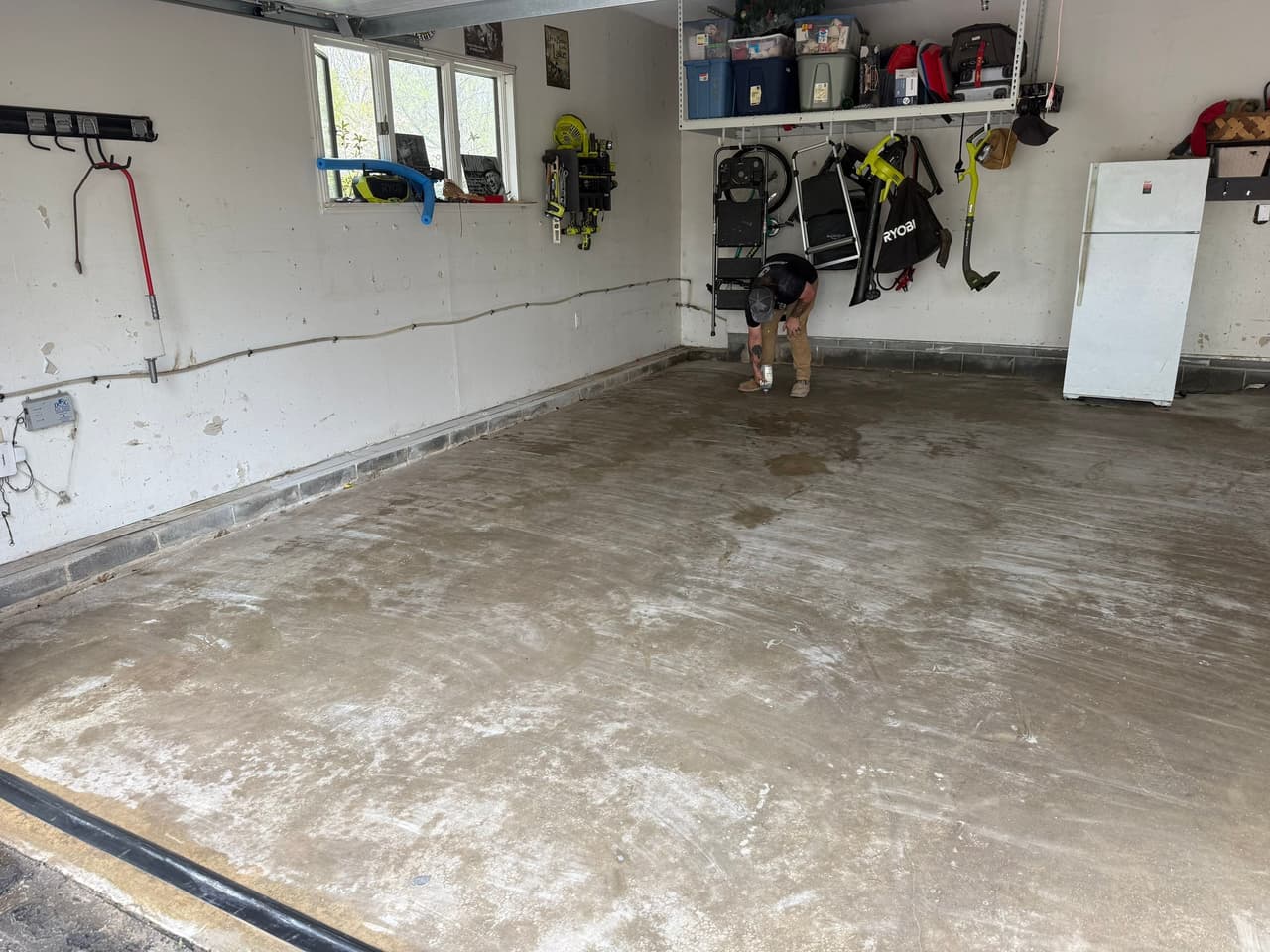 HydroHelp911 Crawl Space & Foundation Repair technician inspecting a cracked concrete garage floor with efflorescence.