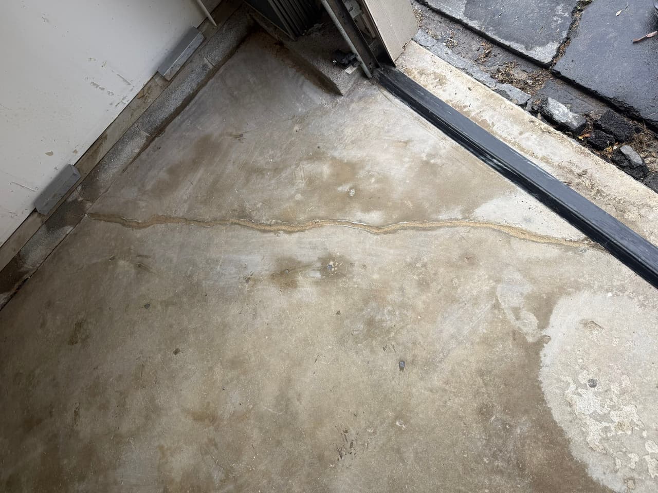 HydroHelp911 Crawl Space & Foundation Repair inspecting a cracked concrete garage floor for settlement signs.