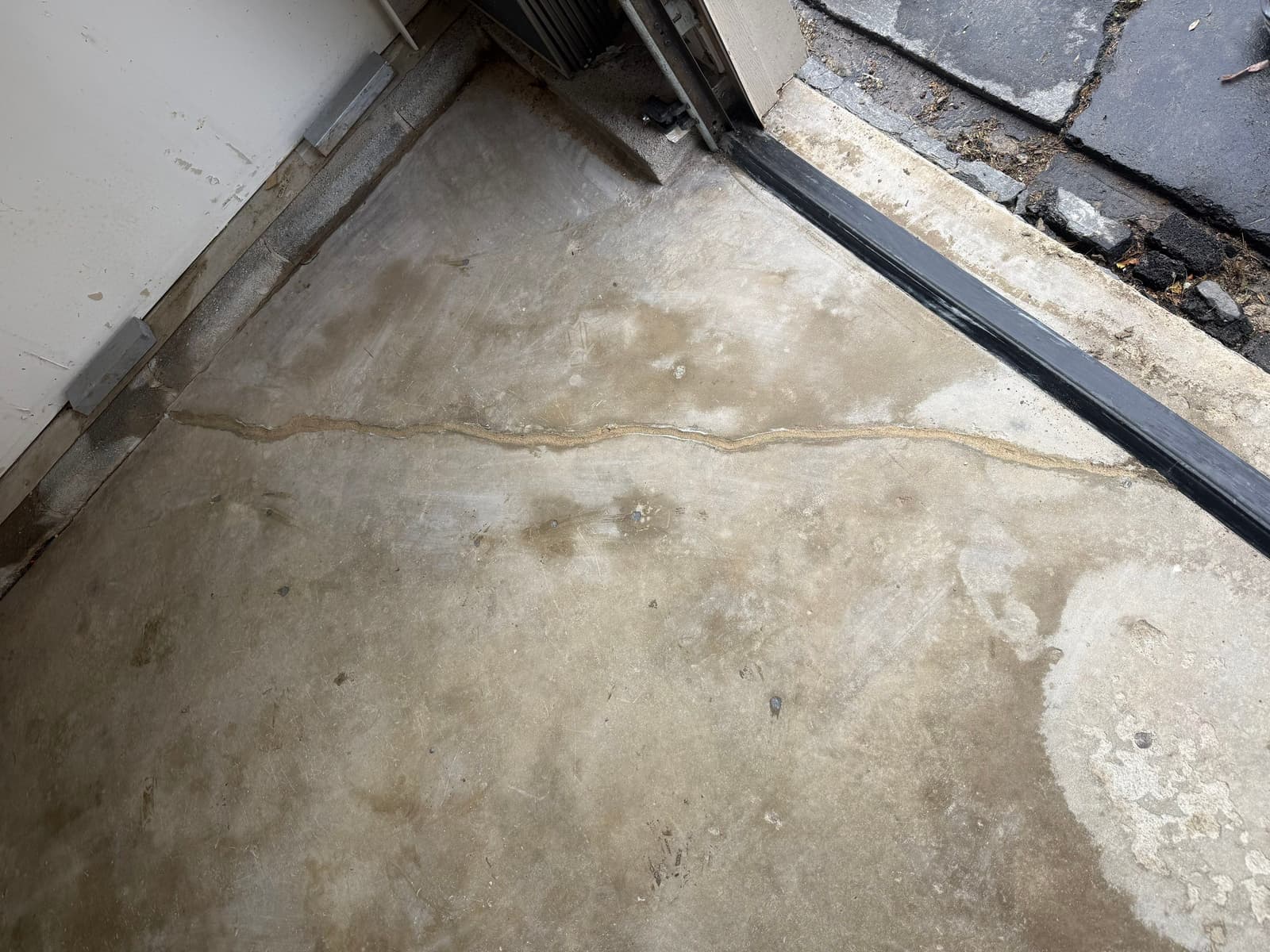 HydroHelp911 Crawl Space & Foundation Repair inspecting a cracked concrete garage floor for settlement signs.