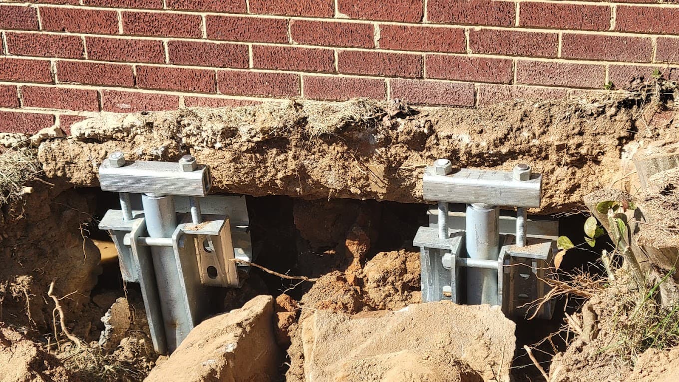 HydroHelp911 Crawl Space & Foundation Repair installing steel piers to stabilize a home's settling foundation.