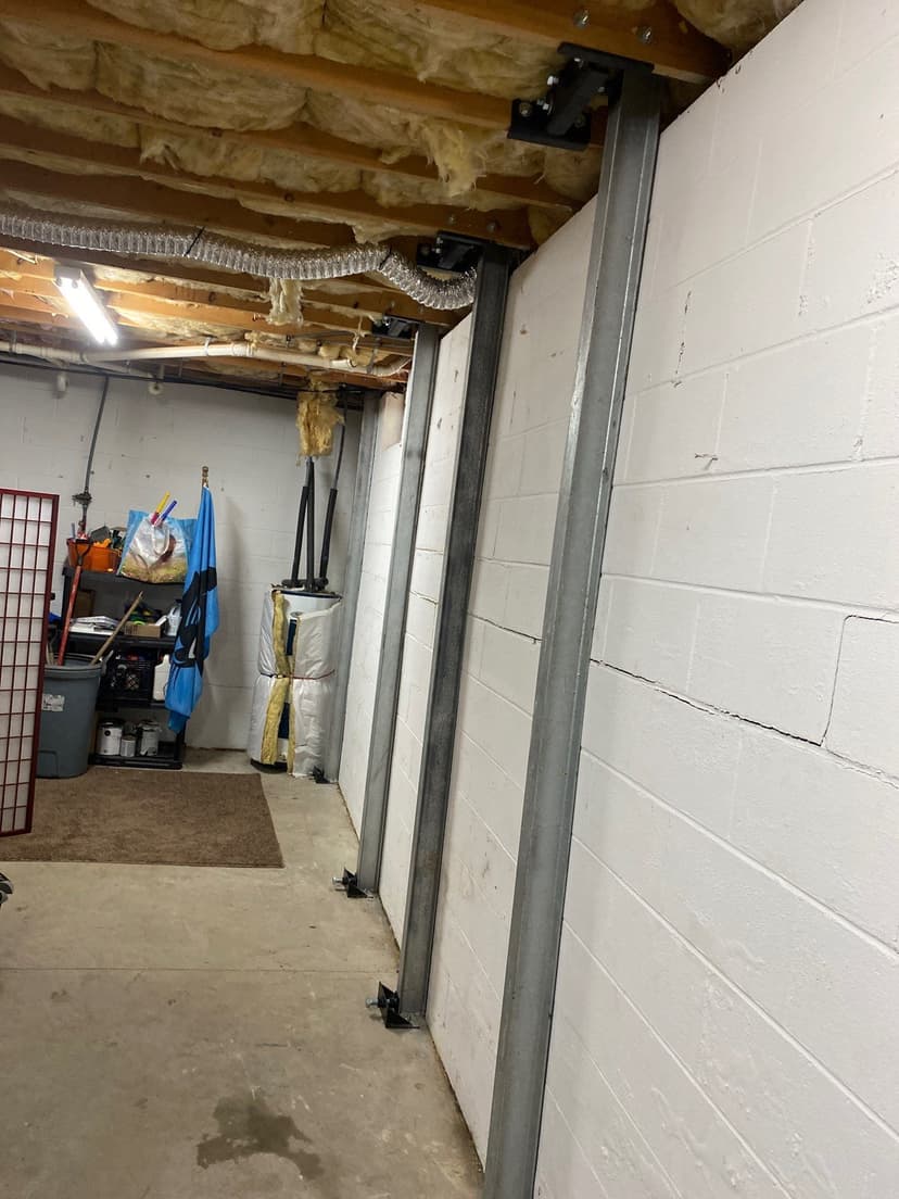 HydroHelp911 Crawl Space & Foundation Repair installing I-beam wall bracing to stabilize a basement foundation wall.