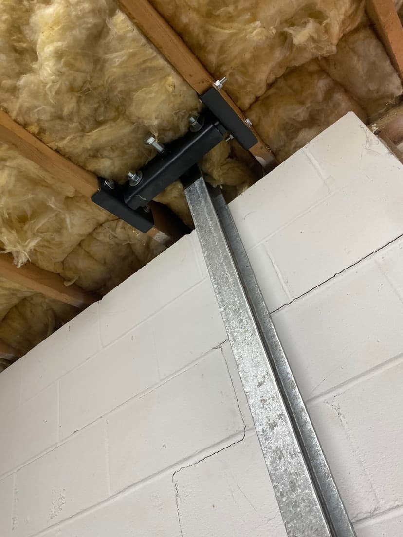 HydroHelp911 Crawl Space & Foundation Repair installing steel I-beam wall bracing to stabilize a cracked basement block