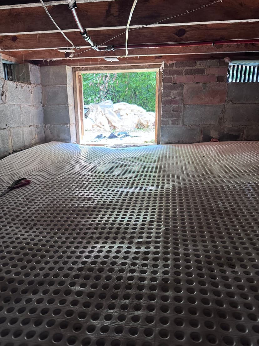 HydroHelp911 Crawl Space & Foundation Repair installing drainage matting in a crawl space with exposed joists