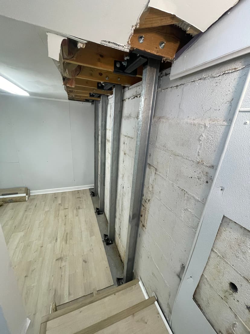 HydroHelp911 Crawl Space & Foundation Repair installing I-beam wall bracing for a bowing basement wall.