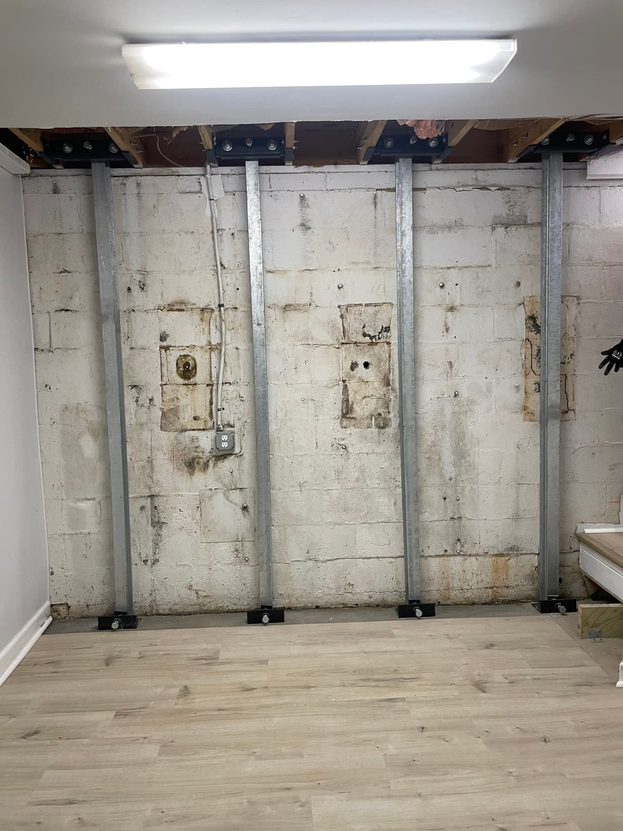 HydroHelp911 Crawl Space & Foundation Repair installing steel I-beams to reinforce a bowing basement foundation wall.