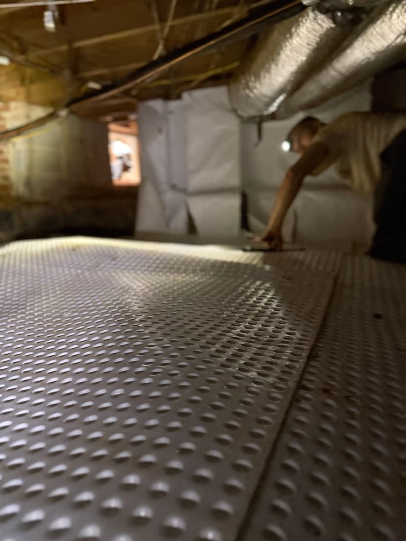 HydroHelp911 Crawl Space & Foundation Repair crew installing a crawl space encapsulation system with drainage matting.