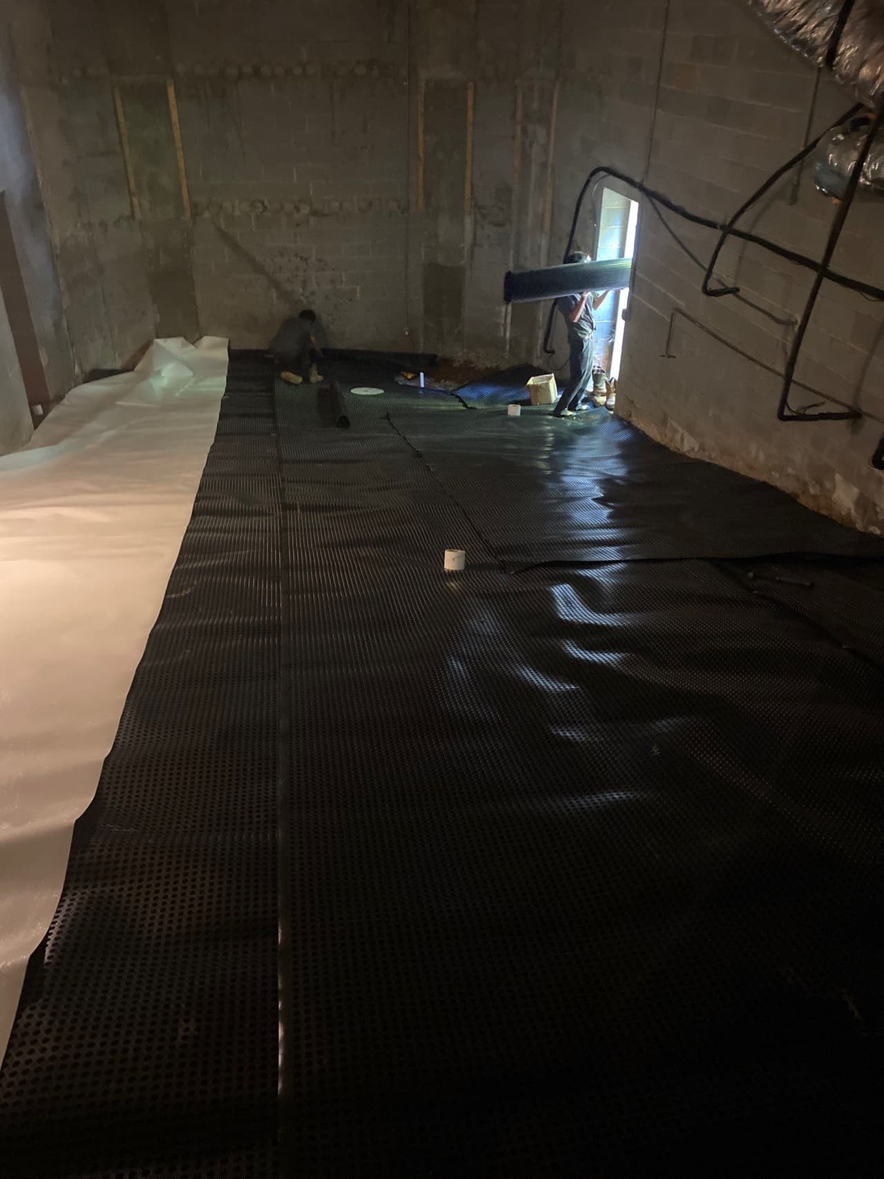 HydroHelp911 Crawl Space & Foundation Repair crew installing drainage matting in a crawl space.