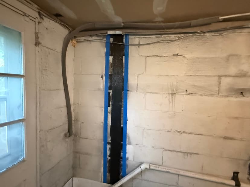 HydroHelp911 Crawl Space & Foundation Repair installing carbon fiber reinforcement straps on a basement wall.