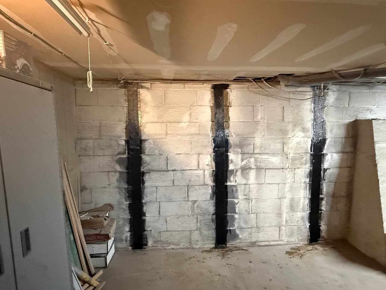 HydroHelp911 Crawl Space & Foundation Repair installing carbon fiber reinforcement on a bowing basement wall.