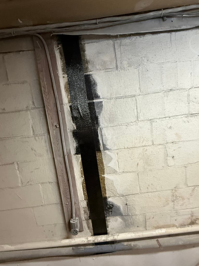 HydroHelp911 Crawl Space & Foundation Repair installing carbon fiber reinforcement straps on a basement wall.