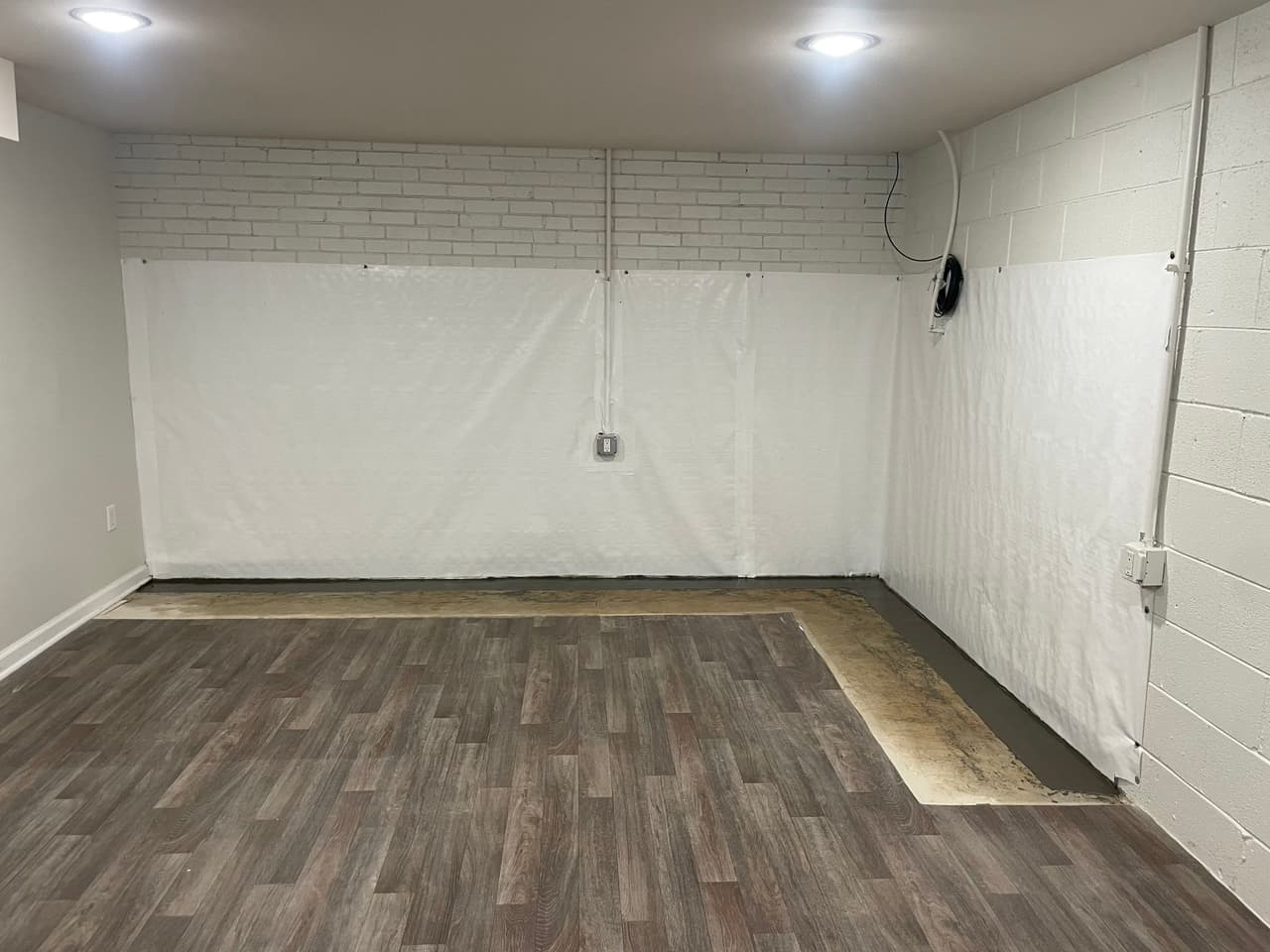 HydroHelp911 Crawl Space & Foundation Repair installing interior waterproofing and a vapor barrier in a basement.