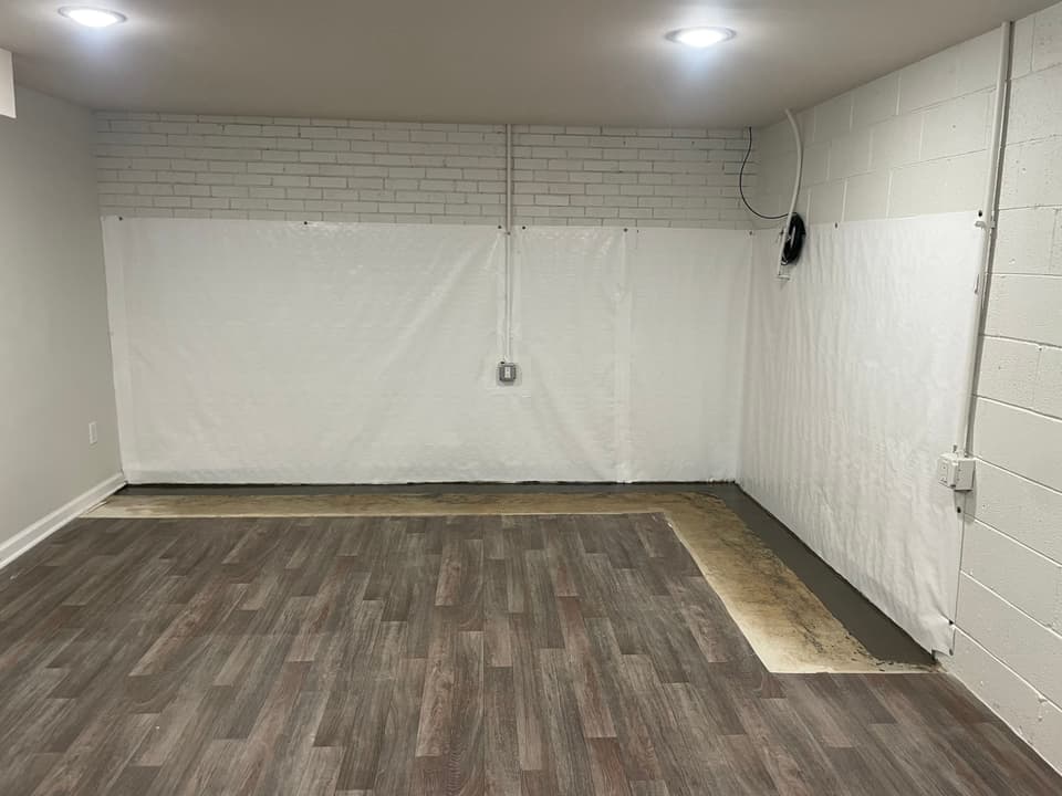 HydroHelp911 Crawl Space & Foundation Repair installing interior waterproofing and a vapor barrier in a basement.