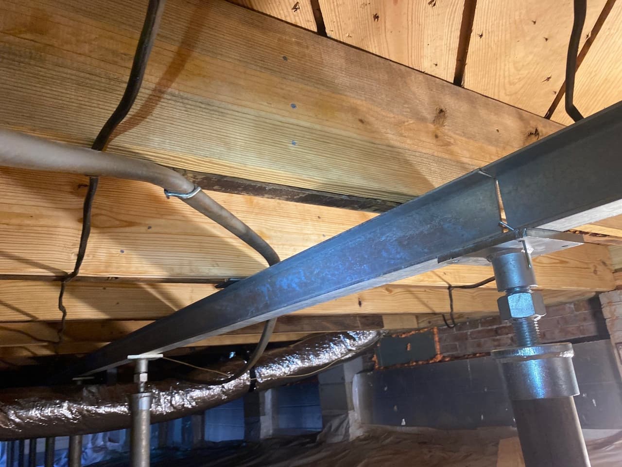 HydroHelp911 Crawl Space & Foundation Repair installing steel I-beam and crawl space jacks to stabilize sagging floors.