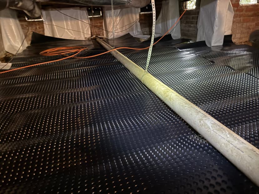 HydroHelp911 Crawl Space & Foundation Repair installing drainage matting as part of a crawl space encapsulation.