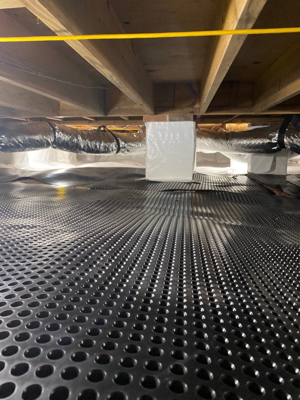 HydroHelp911 Crawl Space & Foundation Repair crew installing a vapor barrier and drainage matting in a crawl space