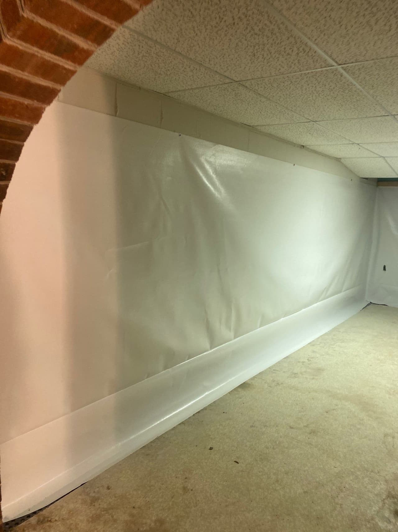 HydroHelp911 Crawl Space & Foundation Repair installing a white vapor barrier and wall liner in a basement.