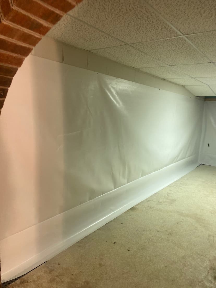 HydroHelp911 Crawl Space & Foundation Repair installing a white vapor barrier and wall liner in a basement.