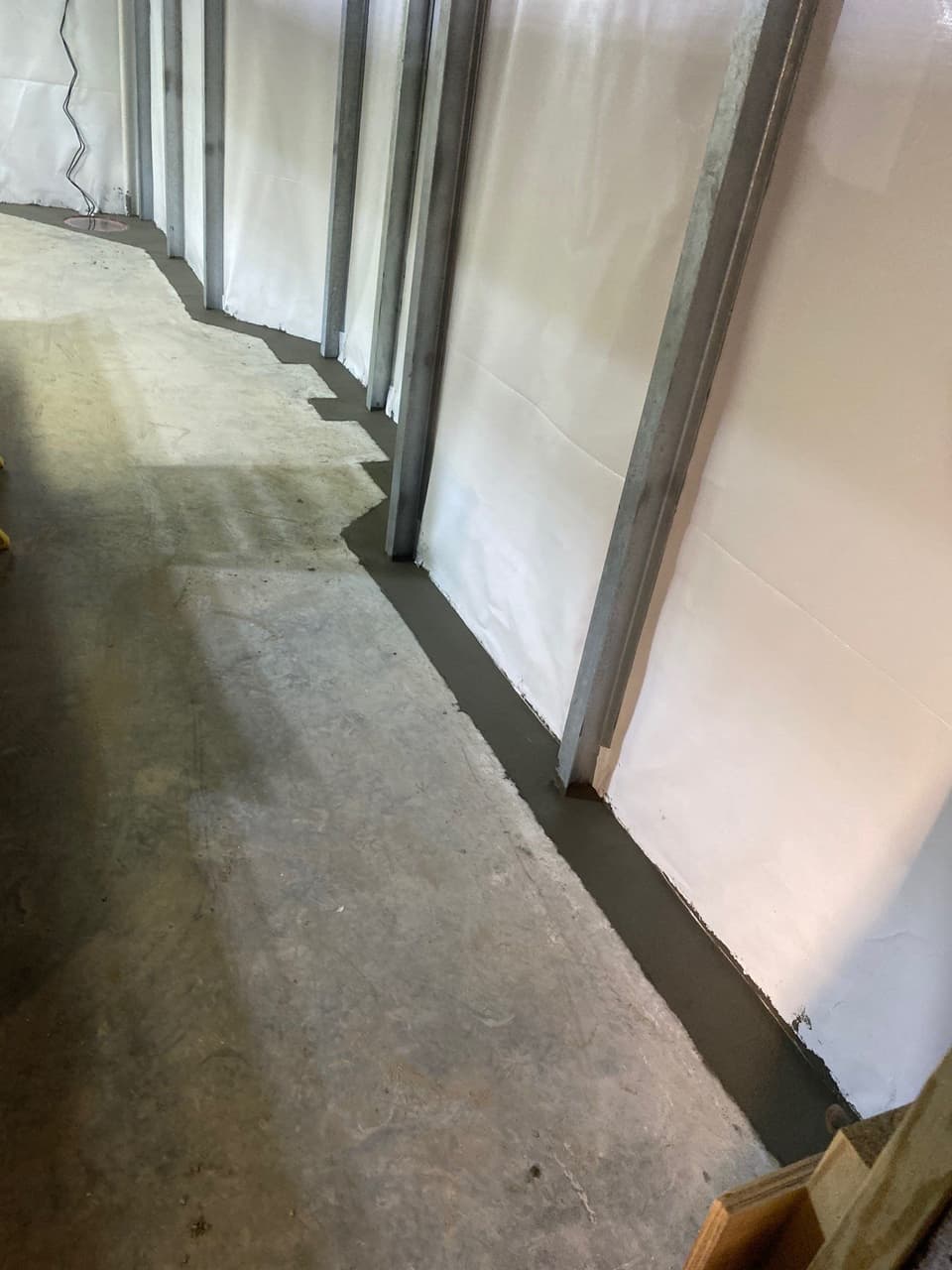 HydroHelp911 Crawl Space & Foundation Repair installing an interior drainage system and vapor barrier in a basement.