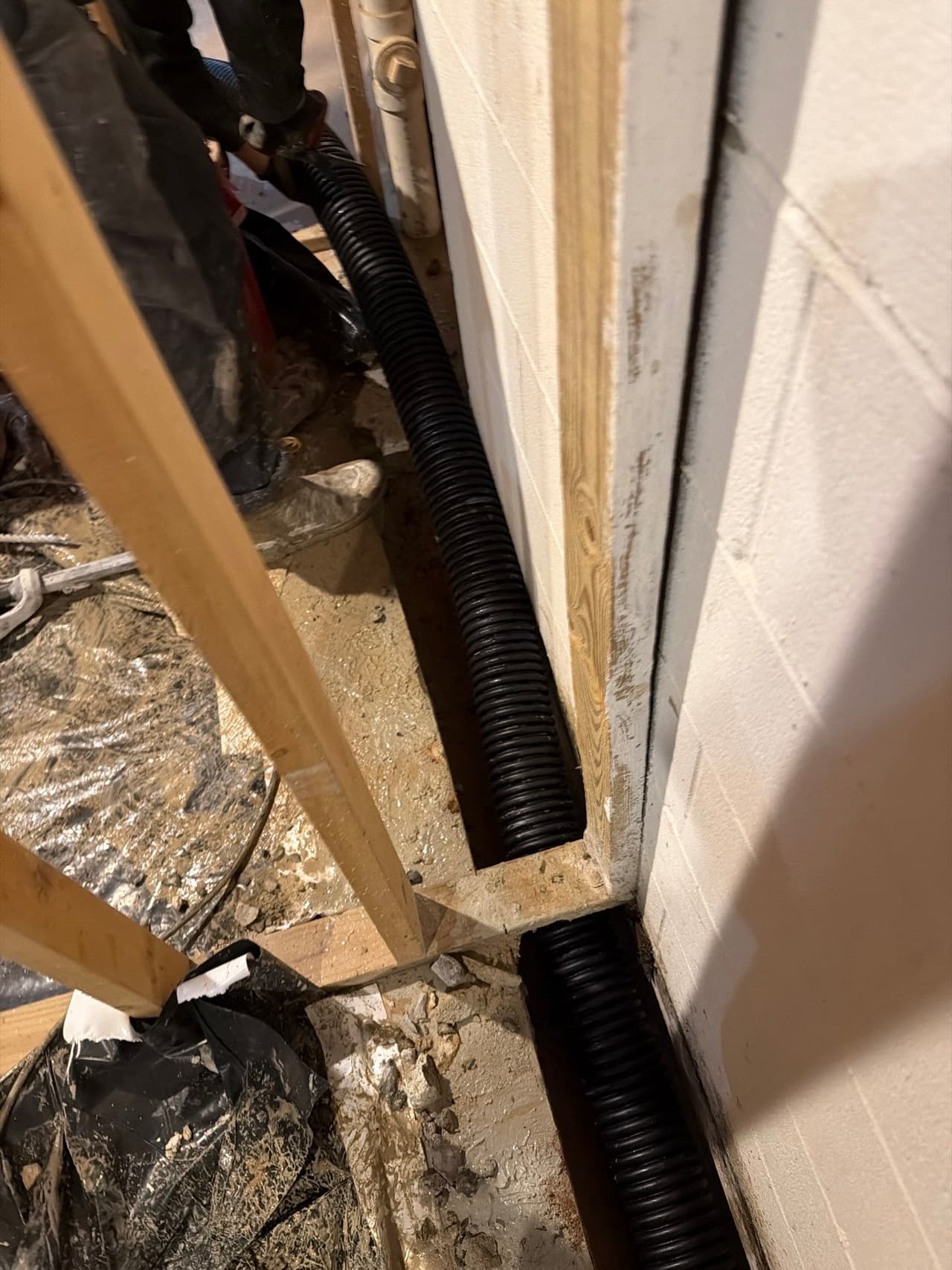 HydroHelp911 Crawl Space & Foundation Repair installing an interior drainage system with corrugated pipe in a basement.