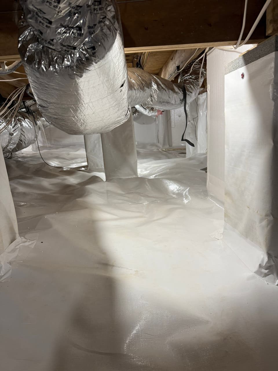 HydroHelp911 Crawl Space & Foundation Repair installing a white crawl space vapor barrier for encapsulation.