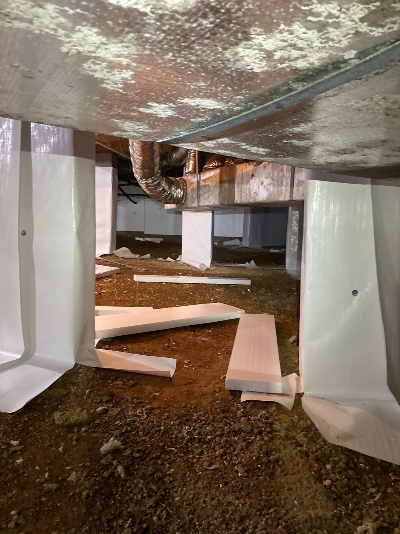 HydroHelp911 Crawl Space & Foundation Repair installing a white vapor barrier and insulation in a crawl space.