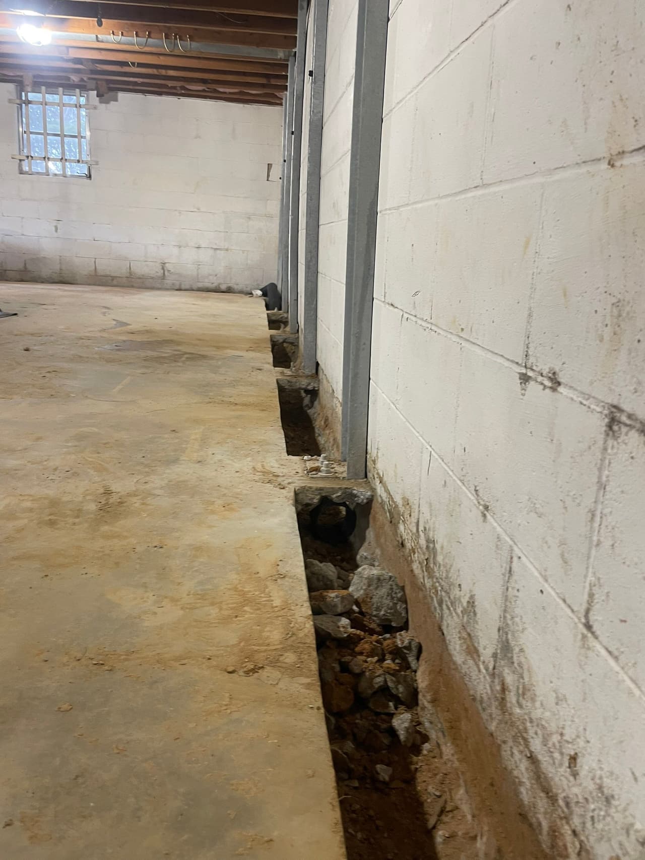 HydroHelp911 Crawl Space & Foundation Repair installing I-beam wall bracing and interior drainage in a basement.