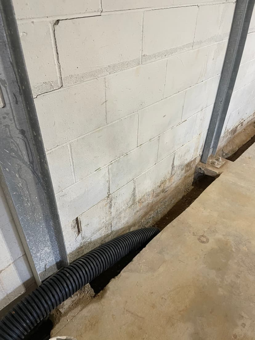 HydroHelp911 Crawl Space & Foundation Repair installing an interior drainage system with I-beam wall bracing in a basement.