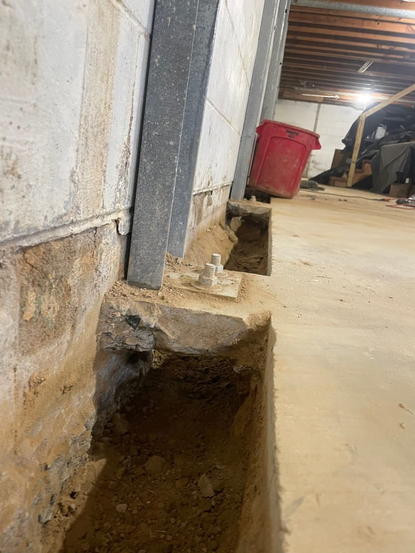 HydroHelp911 Crawl Space & Foundation Repair installing I-beam wall bracing in a basement to stabilize a bowing foundation
