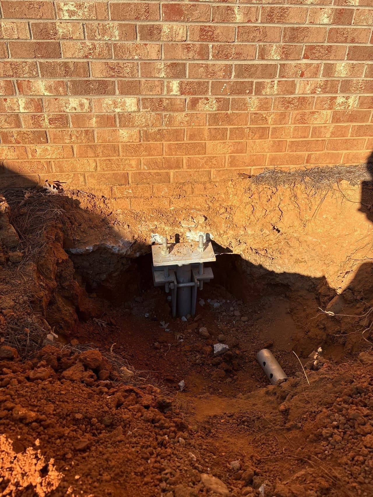 HydroHelp911 Crawl Space & Foundation Repair installing steel push piers for foundation underpinning on a brick foundation.