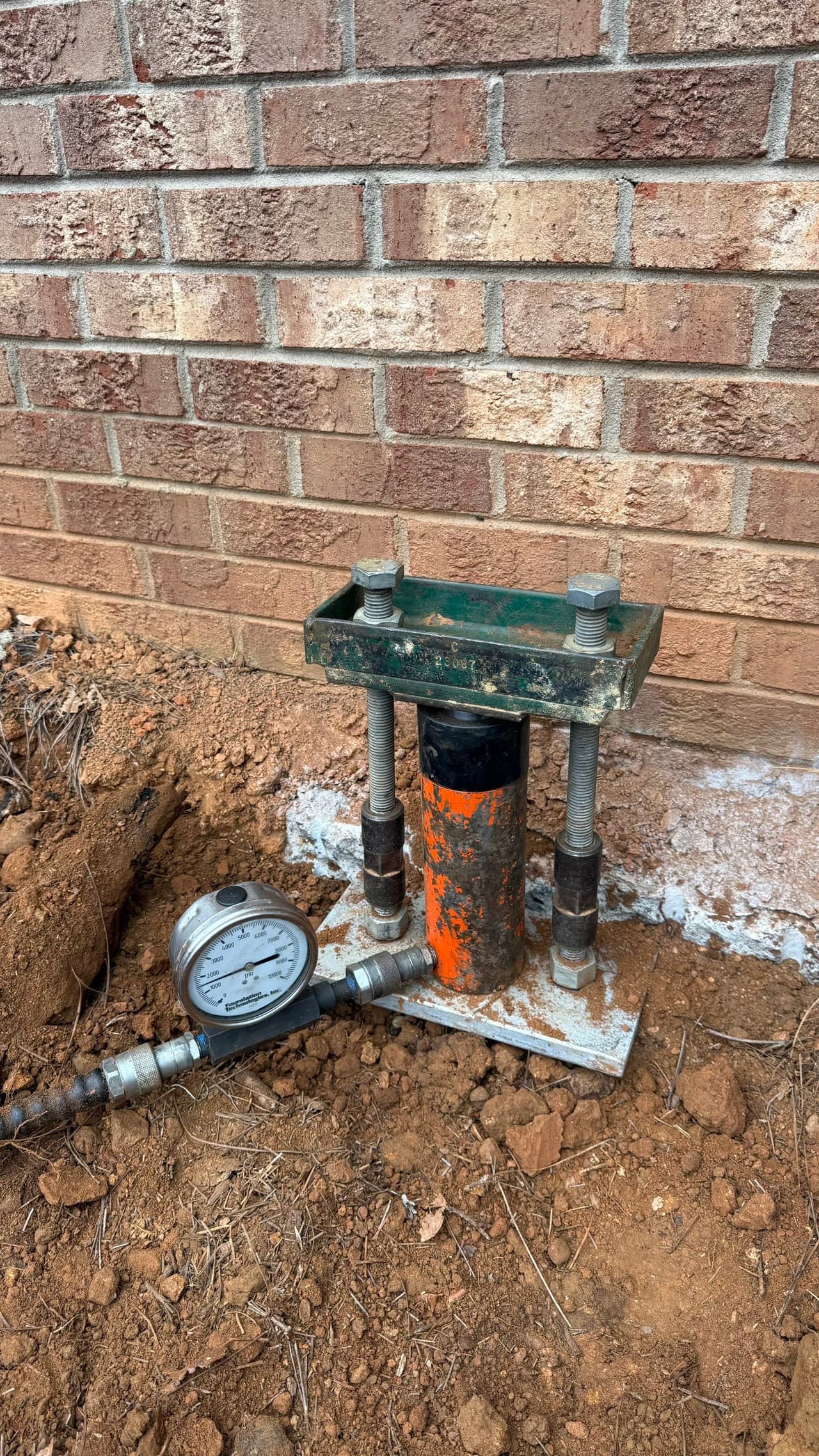 HydroHelp911 Crawl Space & Foundation Repair installing push piers with a hydraulic ram and footing bracket.