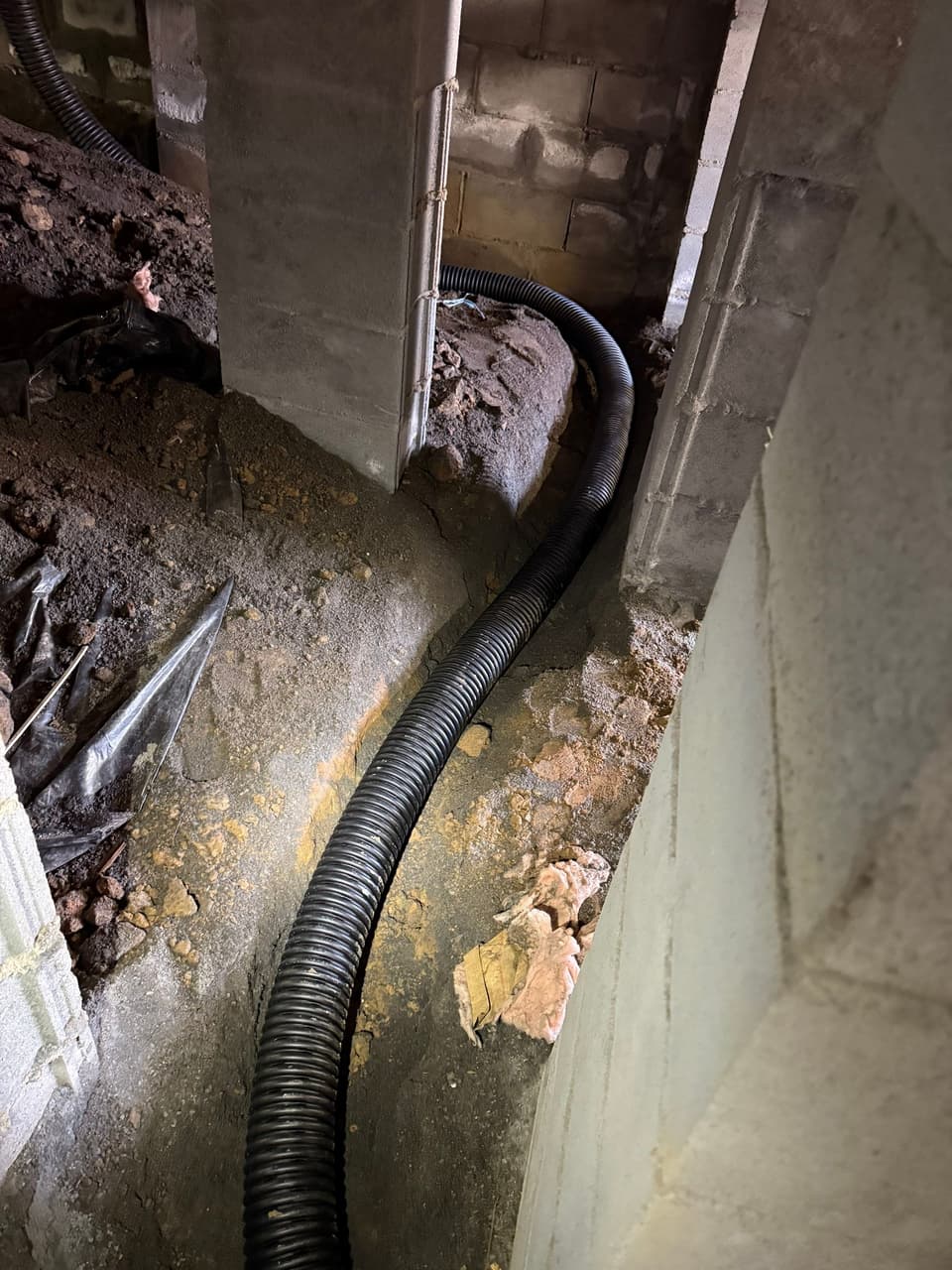 HydroHelp911 Crawl Space & Foundation Repair installing a perforated drainage pipe in a crawl space drainage trench.