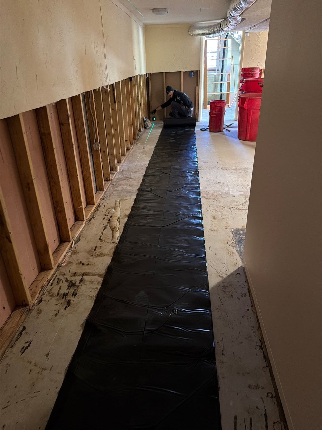 HydroHelp911 Crawl Space & Foundation Repair crew installing interior basement waterproofing along a framed wall.