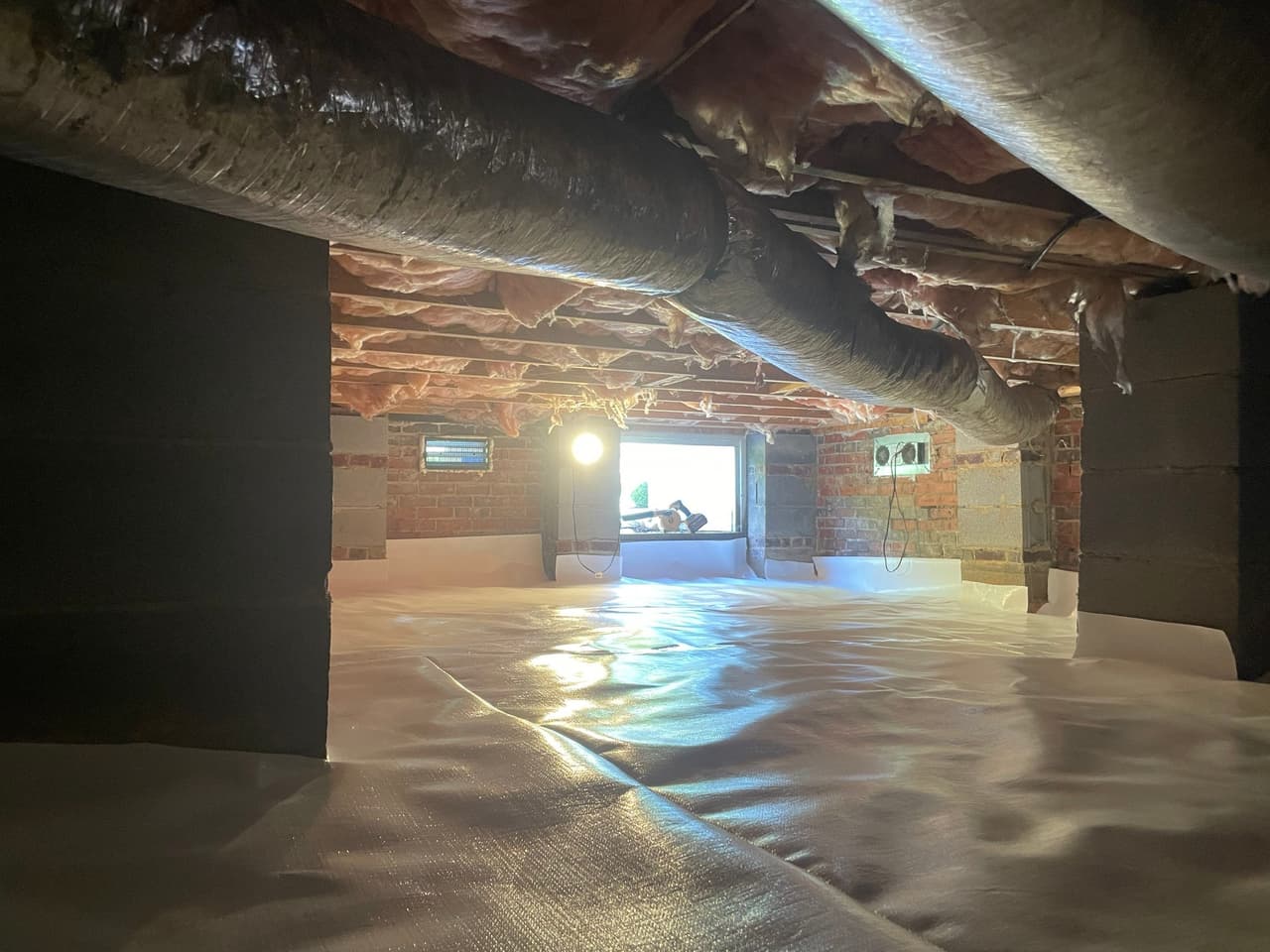HydroHelp911 Crawl Space & Foundation Repair completed crawl space encapsulation with a white vapor barrier and insulation.
