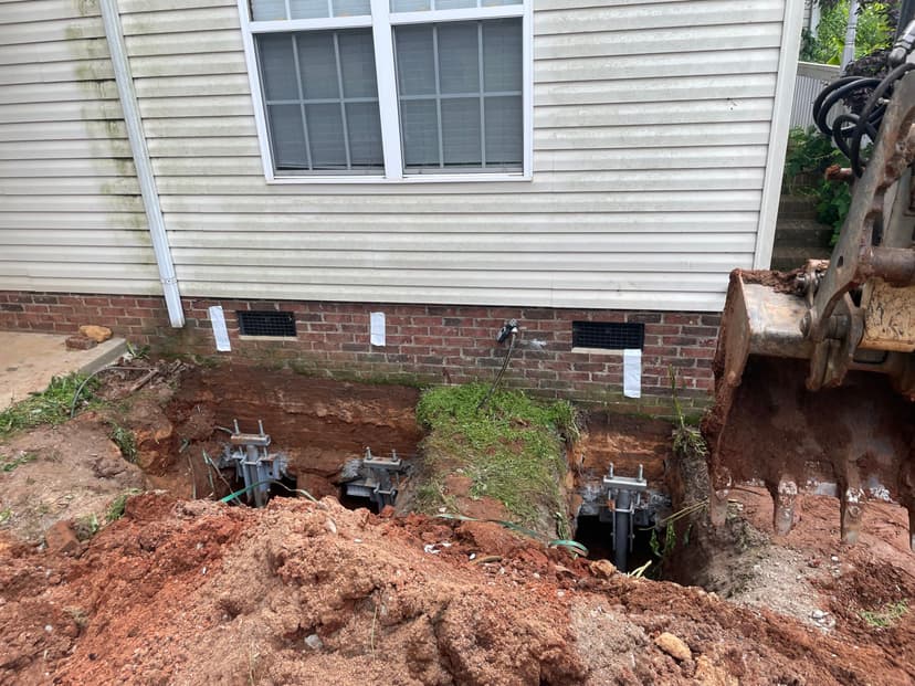 HydroHelp911 Crawl Space & Foundation Repair installing steel piers and footing brackets for foundation underpinning.