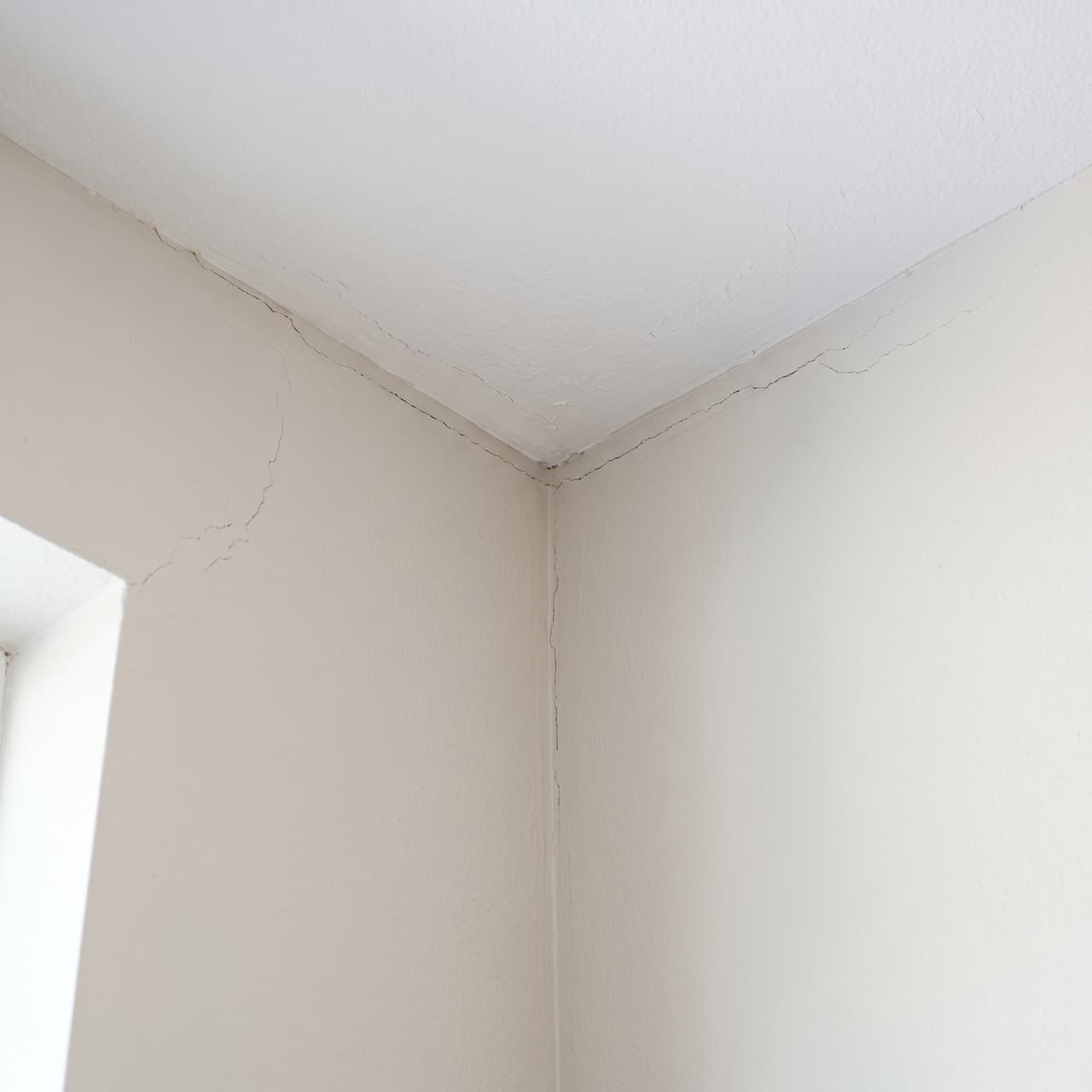 Inspecting diagonal cracks in drywall, ceiling, and door frame.